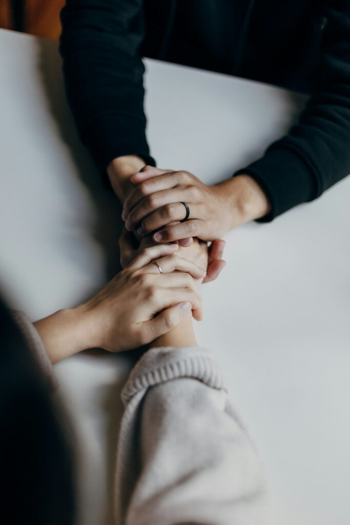 Two people holding hands across a table in comfort